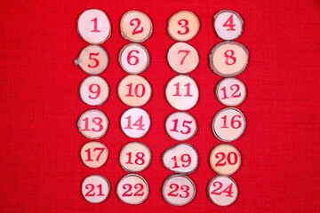 Wooden decorative 1 to 24 log button designs against a bright red stitch background. Ideal to illustrate Christmas advent countdown.