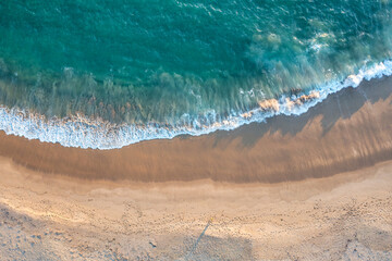 Plakat Beach sand sea water summer background. Sand beach desert texture. White foam wave sandy seashore top view.