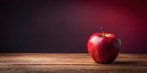 A lone red apple sits on a wooden table against a maroon background, autumn, decoration