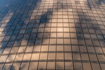 Windows of building at sunset. Reflection of the sky in the window glass. Skyscrapers in business district against blue sky. Looking up high-rise office buildings. Angled view.