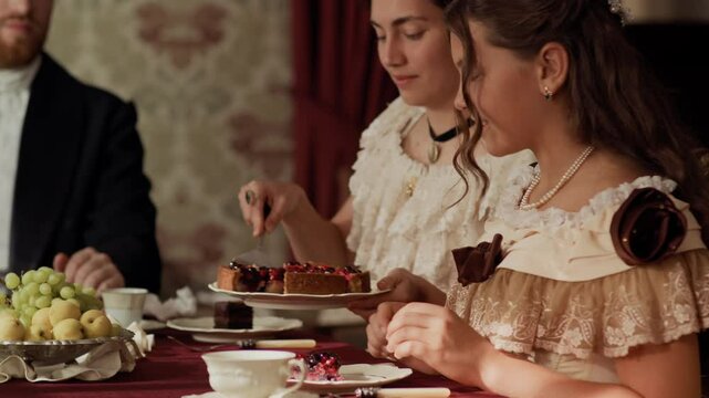 Waist up shot of two women and one man in 19th century attire sitting at formal dining table, enjoying dessert topped with berries