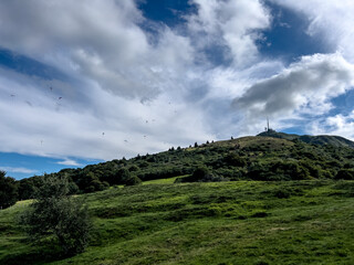 paragliders next to antenna of puy de dome clouds sky green landscape