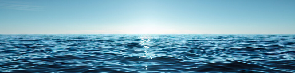 Fototapeta premium A calm blue sea, its surface dotted with small whitecaps under a clear sky.