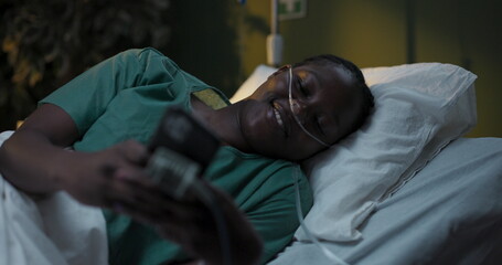 Fototapeta premium Patient with oxygen tube in hospital uses phone in hospital ward.