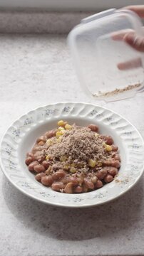 Hands adding ground beef to a Colombian beans preparation