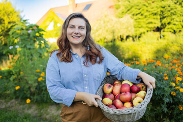 Fresh ripe apples from the orchard trees collected by the beautiful woman farmer she posing with...