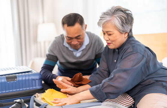 Senior couple packing suitcase for travel, asian elderly preparing for vacation, grandparents organizing luggage, retirement travel planning enjoying trip preparation packing essentials for holiday