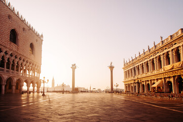 Fototapeta premium Breathtaking Sunrise at San Marco Square in Venice, casting warm light on the historical architecture and quiet cobblestone pathways, creating a serene atmosphere for early morning wanderers. Italy