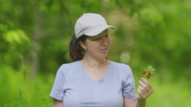Woman With A Branch Of Wild Strawberries. Middle Aged Woman Holding A Branch Of Wild Strawberries In Her Hands. Gimbal shot.