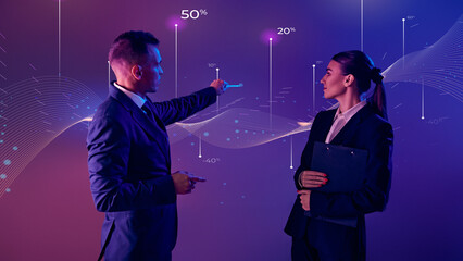 Corporate speaker with his assistant analyzes financial data trends using interactive chart as...