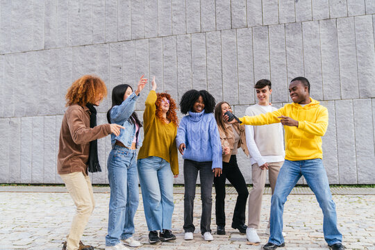 Group of multiethnic young people having fun singing karaoke outdoors