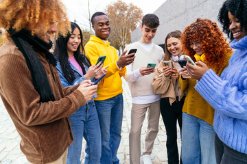 Multiethnic friends using smartphones together outdoors
