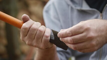Checking the sharpness of a slightly worn axe blade by touching the edge with fingers before sharpening.