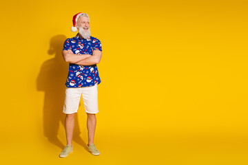 Full body portrait of stylish santa folded arms look empty space wear christmas print shirt isolated on yellow color background