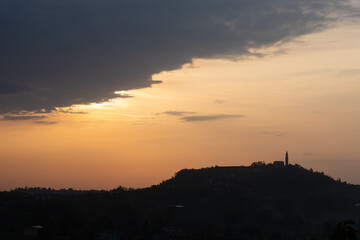 La silhouette del borgo di Formeniga, in provincia di Treviso, Veneto, Italia, contro il cielo arancione all'alba di un giorno d'autunno, lungo il cammino delle colline del Prosecco
