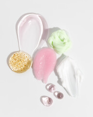 Composition of various cosmetic scrub, creams and serum smear on white background. Beauty texture. Sample of a cosmetic product