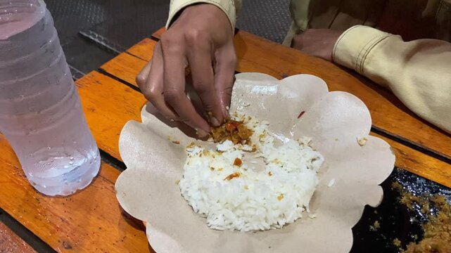 Eating "Ayam Geprek" Indonesian Traditional Food with chili Suce at the restaurant