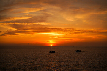 Breathtaking sunset scene, tourist boat in beautiful seascape and sky reflecting on the tranquil waters, creating a serene and picturesque setting.High view form Promthep Cape, Phuket, Thailand.