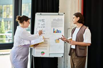 A young plus size woman enthusiastically discusses charts with her male friend in an office.