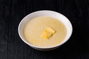 rice porridge with milk and butter. on a black wooden background
