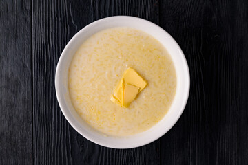 rice porridge with milk and butter. on a black wooden background