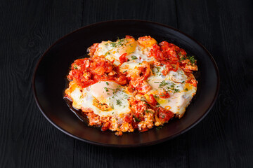 scrambled eggs with vegetables. on a black wooden background
