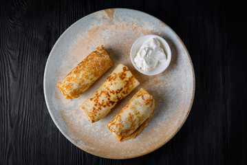 breakfast, pancakes with minced meat and sour cream. on a black wooden background