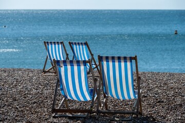 blue and white striped deckchairs on the beach with the sea in the background  Brighton Sussex England