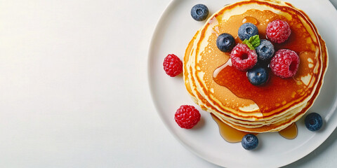 Pancakes topped with berries and maple syrup.