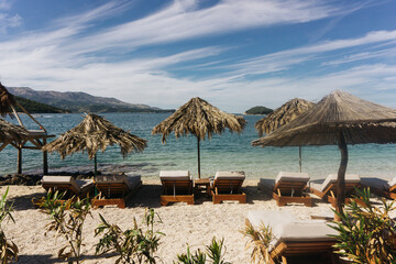 Palm beach with sun loungers and umbrellas. Exotic island vacation setting on a sunny summer day. Resort atmosphere by the sea, perfect for relaxation. Tropical paradise with beach bar and clear water