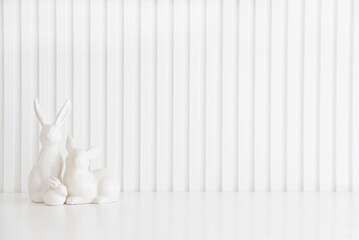 Easter rabbits figurines and eggs on white background. Easter celebration concept. Copy space. Front view