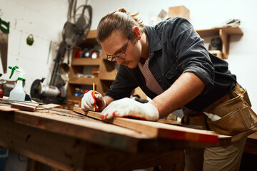 Man, builder and pencil to measure wood at workshop, carpenter and tool for precision design. Male...