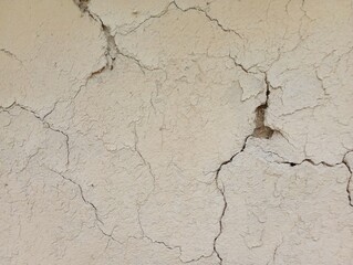 Background of a clay white wall covered with cracks on a lime surface.