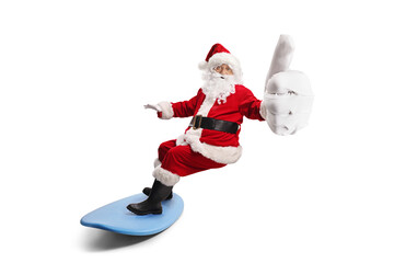Santa claus riding a surfboard and gesturing thumbs up
