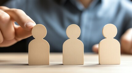 Hand selecting wooden figurines representing teamwork and collaboration.