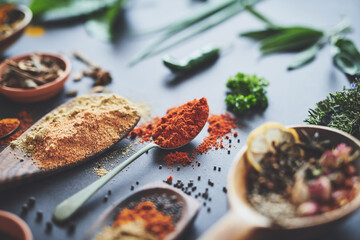 Kitchen, herbs and spices with spoon on counter with ingredients, flavor and seasoning for cooking. Seeds, leaves and above utensils on table for meal prep, curry and variety for food at restaurant