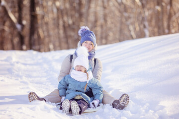 Mother with little daughter slide down from snow slope together sitting in one slide. Winter activities concept image. Happy family time