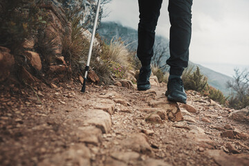 Naklejka premium Hiking, travel and walking pole with shoes in nature for relax, health and adventure. Challenge, wellness and holiday with person and trekking stick for mountain path, fitness and camping vacation