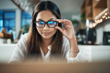 Business, laptop and woman in cafe, glasses and research for web design, clear vision and startup. Happy person, freelancer and entrepreneur with computer, eyewear and online reading in coffee shop