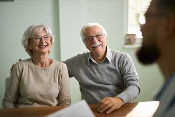 Happy mature couple talking to a doctor in the office.