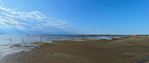 A vast sandy sea beach. Sunset over the sea. Beautiful sunny weather over the sea on a summer afternoon.