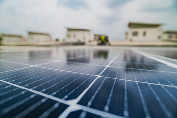 A close up of solar panels with a worker blurred in the background. The focus on the panels emphasizes the importance of renewable energy technology and solar power installations.