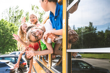 Group of young students attending primary school on a yellow school bus