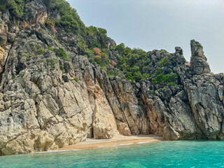 Obraz premium Small sandy beach only accessible by boat is tucked into cove at base of the cliff near Himare, Vlore, Albania. Secluded and peaceful spot to relax. Coastline of Albanian Riviera in Mediterranean sea