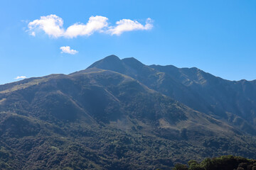 Fototapeta premium Scenic view of majestic Ceraunian mountain range in Albania, with clear blue sky above the peak. slopes are covered in lush green vegetation. Hiking and outdoor activities in Albanian Alps. Wanderlust