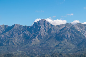 Scenic view of majestic Ceraunian mountain range in Albania, with clear blue sky above the peak. slopes are covered in lush green vegetation. Hiking and outdoor activities in Albanian Alps. Wanderlust