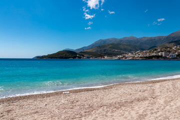 Panoramic view of the picturesque coastline of coastal tourist town Himare, Vlore, Albania. Idyllic sand beach Potami with scenic vistas of majestic Ceraunian mountains. Summer vacation concept