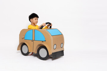 Asian little boy playing with cardboard car isolated on white background, Kid toy diy concept