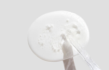 Clear cosmetic gel with bubbles on spatula against neutral background for skincare product visuals