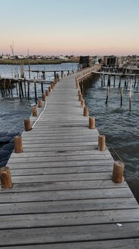 Porto Palafitico in Comporta, Portugal, featuring traditional wooden stilts and rustic fishing boats along the winding pier, capturing the charm of this unique harbor on a calm 